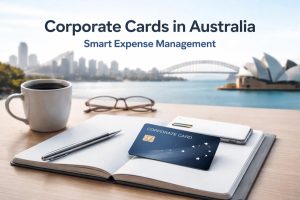 A business workspace overlooking Sydney Harbour with the Harbour Bridge and the Sydney Opera House in the background. On a desk sit an open notebook, pen, smartphone, coffee cup, and a corporate credit card placed on the notebook. The headline “Corporate Cards in Australia – Smart Expense Management” appears at the top, illustrating how businesses in Australia use a corporate credit card to manage company expenses, track spending, and streamline financial administration.